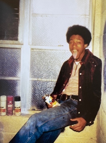 A young Blade sitting in a window with spray cans beside him