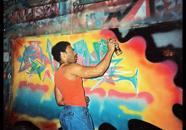 Blade spraying a colourful canvas in his studio